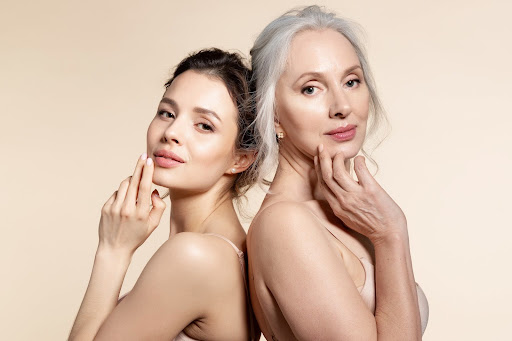 Older and young women enjoying the benefits of hormones for skin health with smooth skin standing back-to-back.