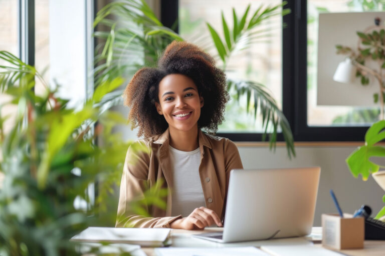 Smiling woman working at a laptop beside a window