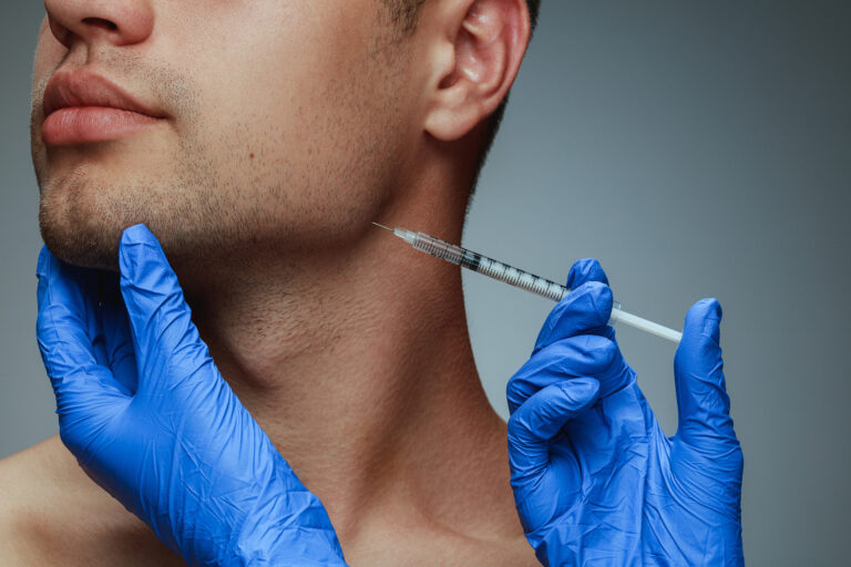 Gloved hands holding a syringe beside a man's jaw