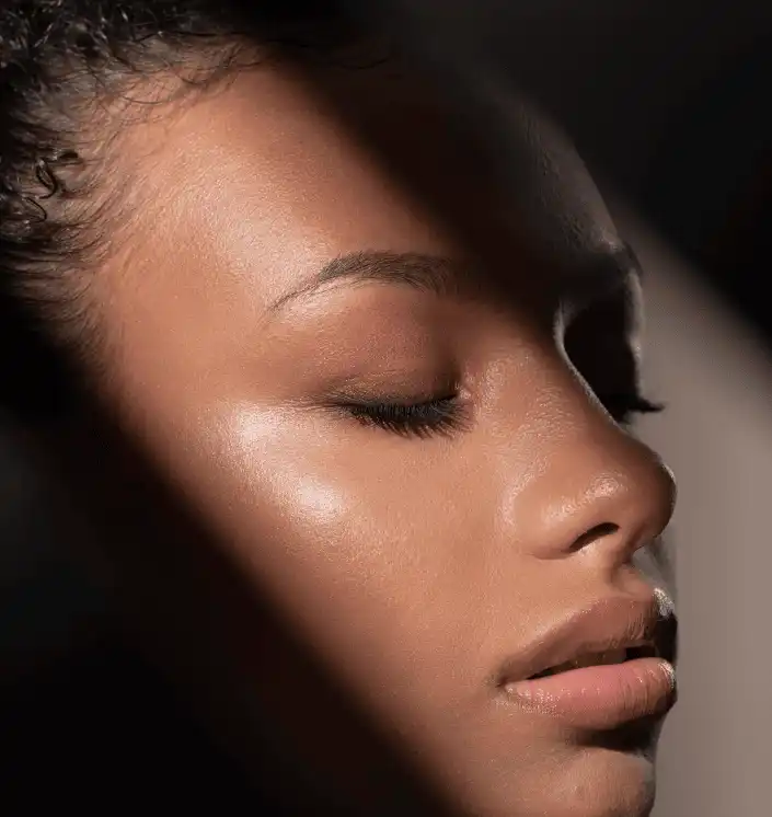 Side view of a woman's face with her eyes closed in a band of light