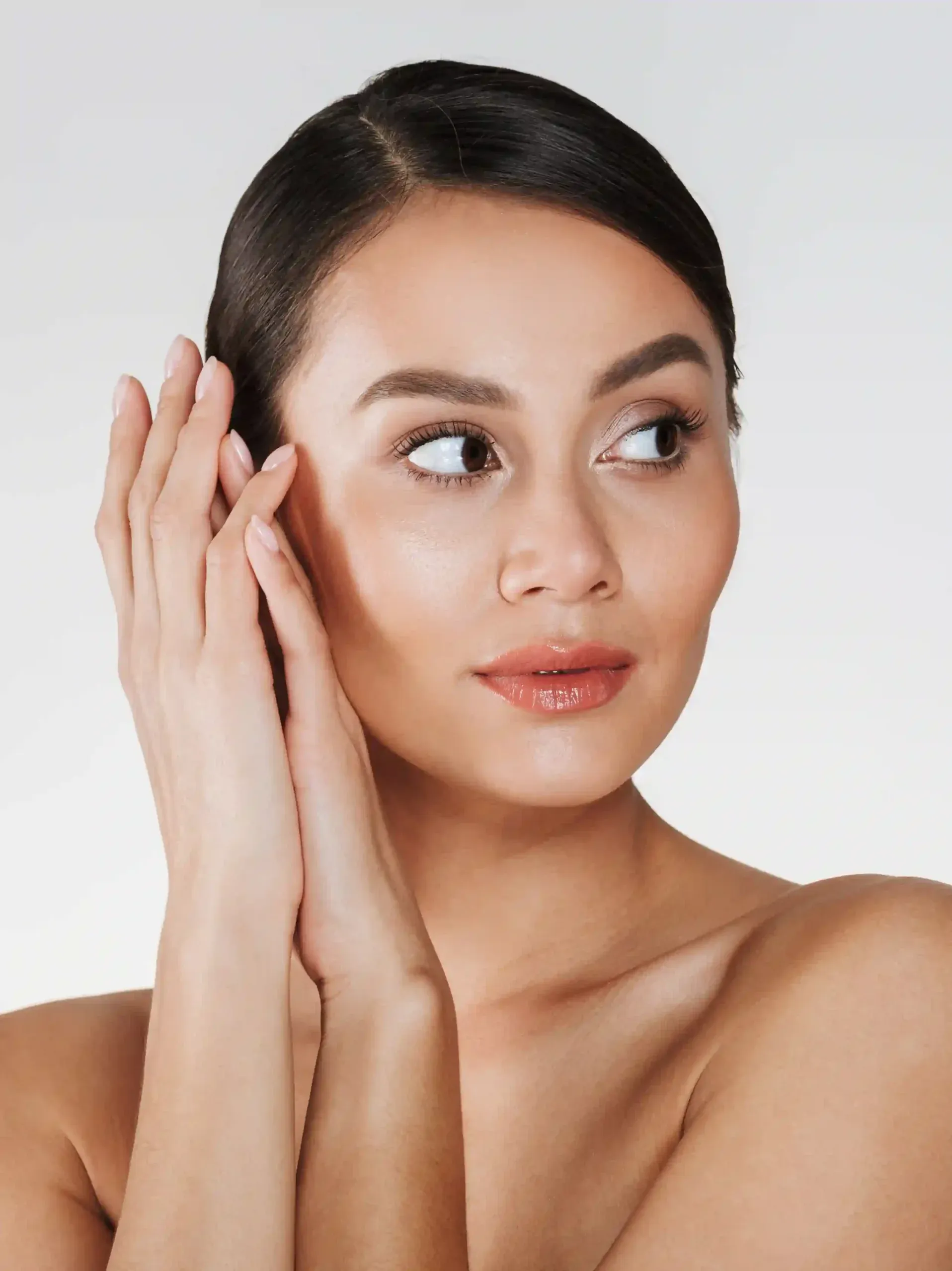 Woman with natural makeup looking sideways with her hands beside her face