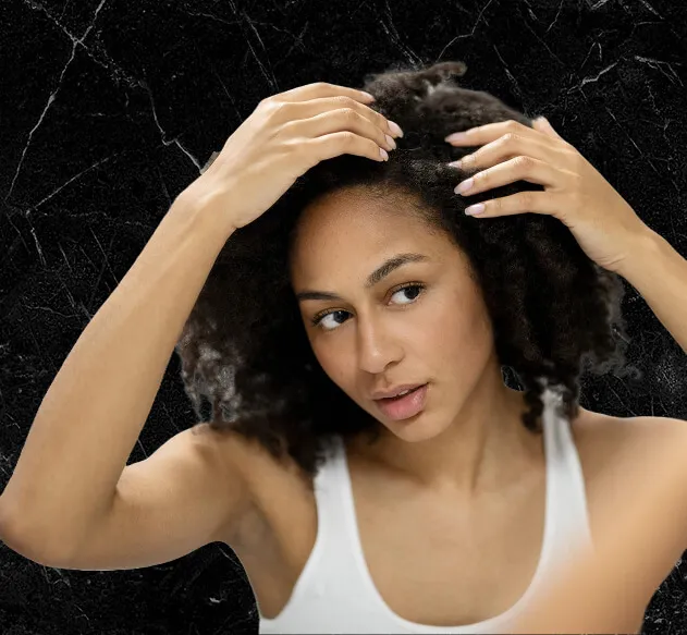 Woman parting her curly hair with both hands to examine her scalp