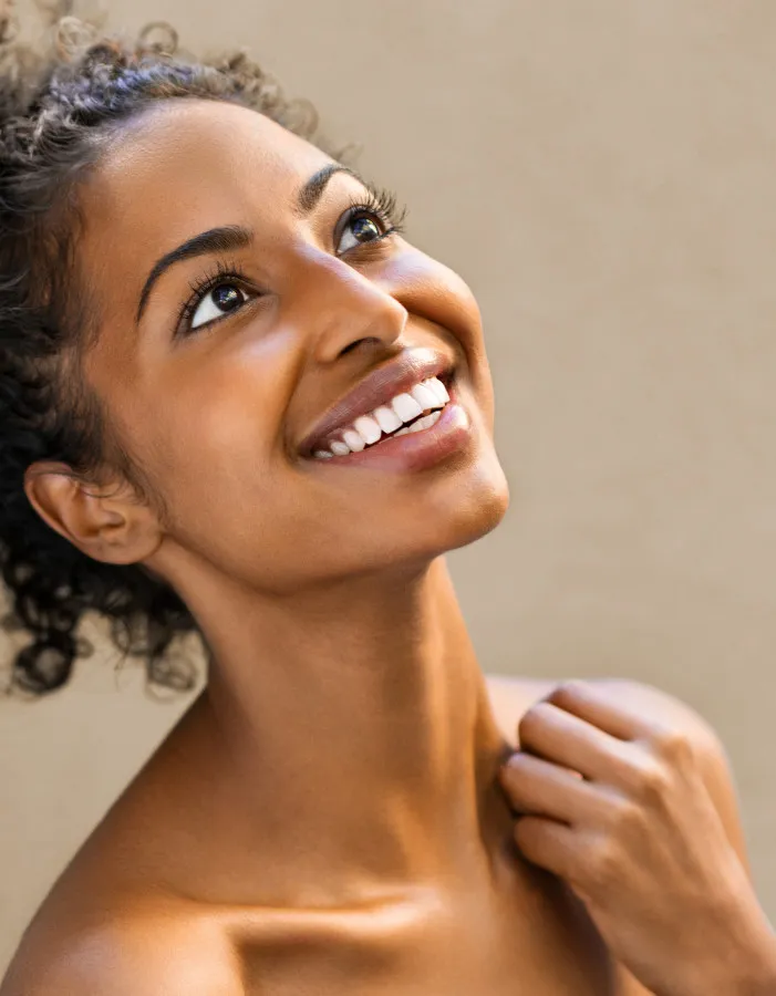 Smiling woman with glowing skin looking upward